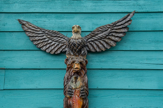 totem pole with bear and eagle in front of a turquoise background
