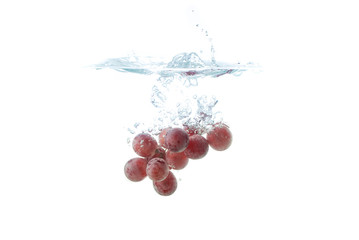 Isolated Red grapes splashing and sinking in water on white background with air bubbles.
