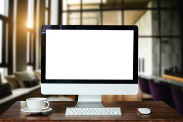 Workspace with computer Monitor, Keyboard, blank screen coffee cup smartphone, and tablet on a table in bright office room interior.