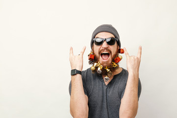 Portrait of cheerful man with christmas decorated beard showing rock sign