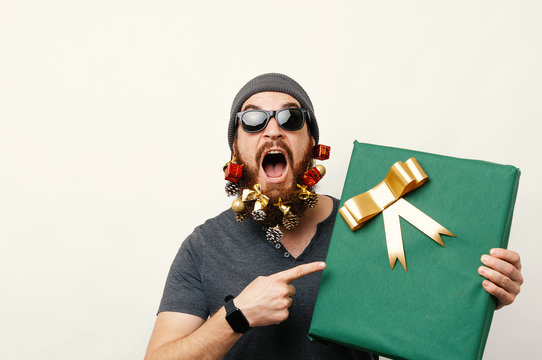 Amazed Man With Christmas Decorated Beard Pointing At Big Gift Box