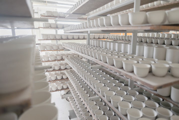 Porcelain factory production of mugs and plates in shelf stacks