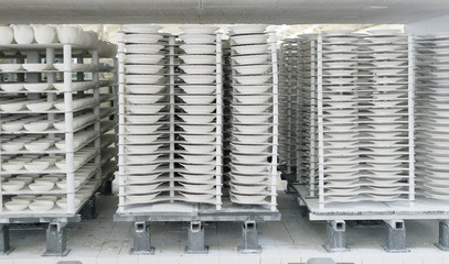 Porcelain factory production of mugs and plates in shelf stacks