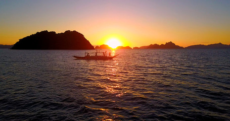 Sunset Silhouette Of Catamaran-Style Boat On Ocean With Tropical Islands In Background - El Nido, Palawan, Philippines