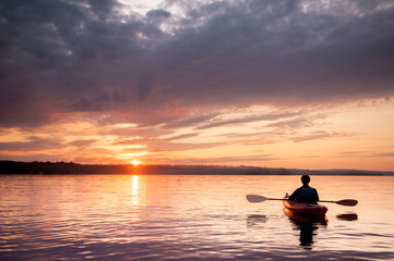 Man in a kayak on the river on the scenic sunset - Powered by Adobe