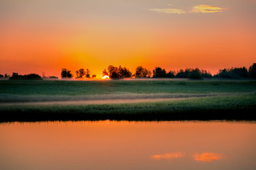 Dawn over a small river on a foggy morning