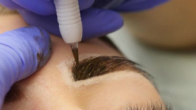 close-up hands of the master doing brows tattoo. permanent eyebrow makeup. 4K