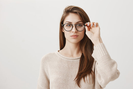 Girlfriend ready to investigate social profile of boyfriend. Portrait of good-looking smart brunette in stylish prescribed glasses looking concentrated at camera, solving issue on char over gray wall