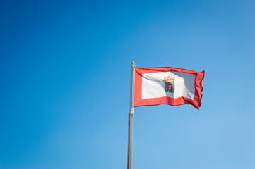 Scenic view of flag of spanish town Gijon, Asturias, Spain. Waving on wind in front of blue clear sky