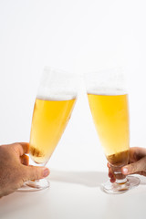 Two full glasses of beer set against a white background