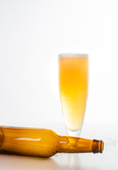 Full glass of beer and a brown beer bottle on its side