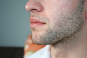A man's face with a slight beard. A few days beard on the guy's chin. Macro picture taken from the...