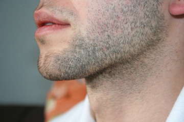 A man's face with a slight beard. A few days beard on the guy's chin. Macro picture taken from the...