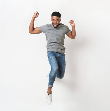 Young black man jumping against white background