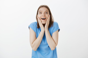 Positive good-looking fair-haired female in blue t-shirt, gasping, standing speechless and amazed...
