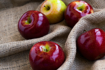 Autumn background with maple leaves and red apples on sackcloth texture background. Red apples on seakcloth.