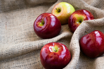 Autumn background with maple leaves and red apples on sackcloth texture background. Red apples on seakcloth.