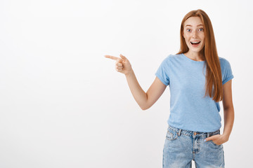 So lucky to visit awesome place. Portrait of charming pleased and happy entertained good-looking redhead girl with freckles gasping with happy impressed smile being amused pointing left