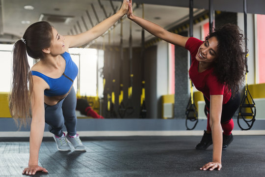 Two multiracial fitness girls doing push ups