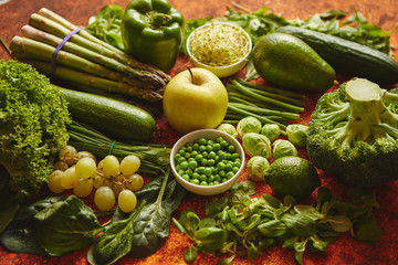 Fresh, natural, green vegetables, fruits and herbs assortment placed on a rusty metal background. Top view.