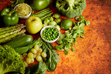 Fresh, natural, green vegetables, fruits and herbs assortment placed on a rusty metal background. Top view.