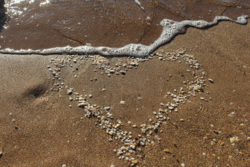Symbol of love - heart of shells on the sandy beach
