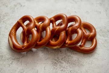 Row of fresh baked brown salty pretzel bread. Placed on stone background. Shot from above with copy space