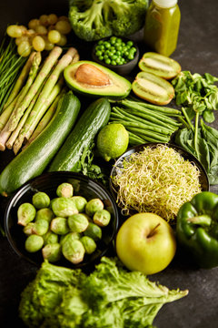 Green healthy food composition with avocado, broccoli, apple smoothie cucomber asparagus kiwi bean. Placed on dark background. Top view.