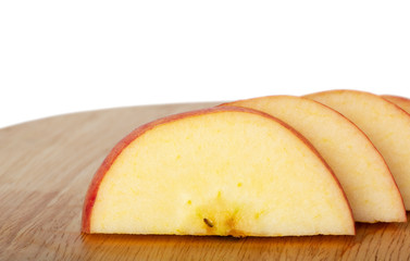 Close up of a sliced red apple on a wooden plate with isolated background.