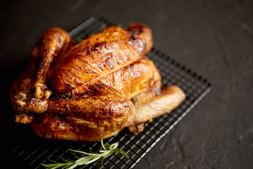 Homemade baked chicken with rosemary herbs. Served on steel black grill frame. Black stone background, Shot from above.