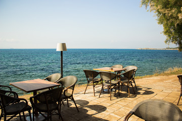 open air patio cafe furniture tables and chairs on shore line of tropic Mediterranean sea in summer hot weather time