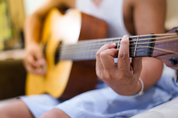 man's hands playing acoustic guitar, close up