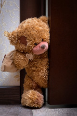Teddy bear with a bag of gifts opens the door to the children's room.