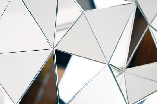 Mirror with crystals in wall, decoration and reflection. Abstract glass background. Polygonal surface. Close-up. Texture.