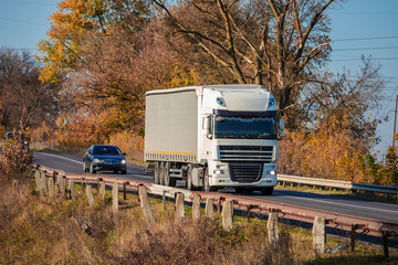 Arriving white truck on the road in a rural landscape at sunset