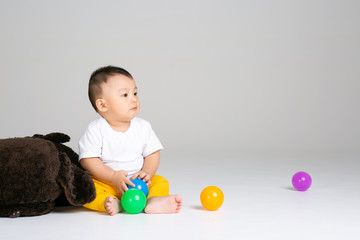 Fototapeta na wymiar funny baby boy sitting on white background with ball
