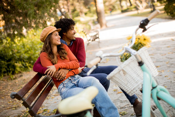 Fototapeta premium Multiratial loving couple sitting on bench in the autumn park