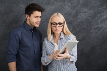 Serious business partners using digital tablet at studio