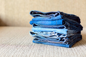 A pile of blue jeans on the grey sofa
