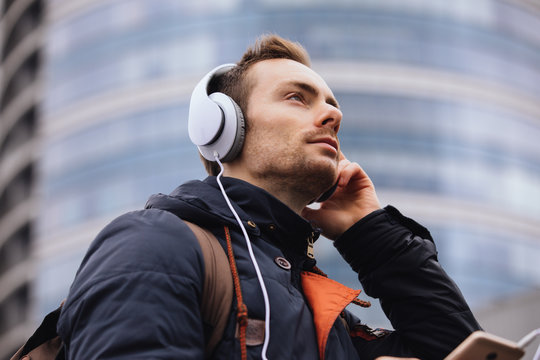 Man in headphones listening to music outdoors in city