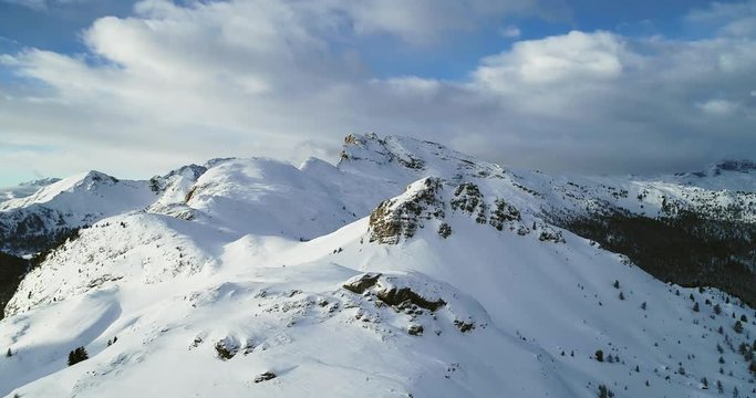 Backward aerial from snowy mounts at Valparola pass.Sunny sunset or sunrise, cloudy sky.Winter Dolomites Italian Alps mountains outdoor nature establisher.4k drone flight