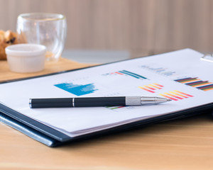 business documents with charts growth, the pen on chart nearby empty snack, closeup pen and blur background