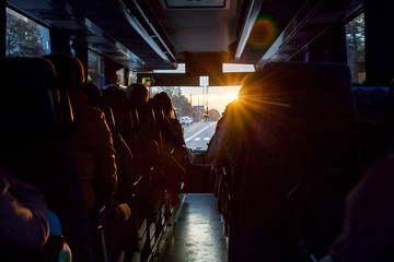 Saloon  of bus with passengers. The light of the sun penetrates through the windshield of the bus. From the window of the tourist bus you can see the road_