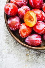 Ripe plums in a copper plate on metallic background