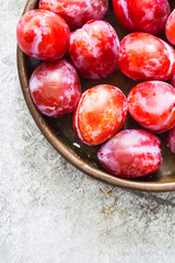 Ripe plums in a copper plate on metallic background