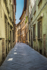 Naklejka premium Tourists wandering in a small street in Lucca, Tuscany