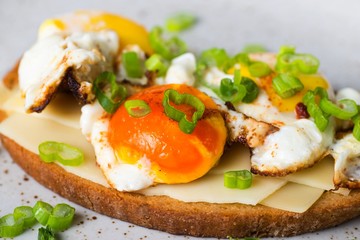 Toasts with fried eggs,cheese and onion shoots.