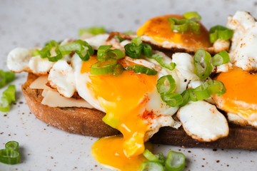 Toast with fried egg,flowing yolk and onion shoots.