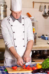 Cook cutting vegetables on the kitchen