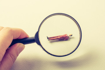 Tiny figurine of man model  under magnifying glass